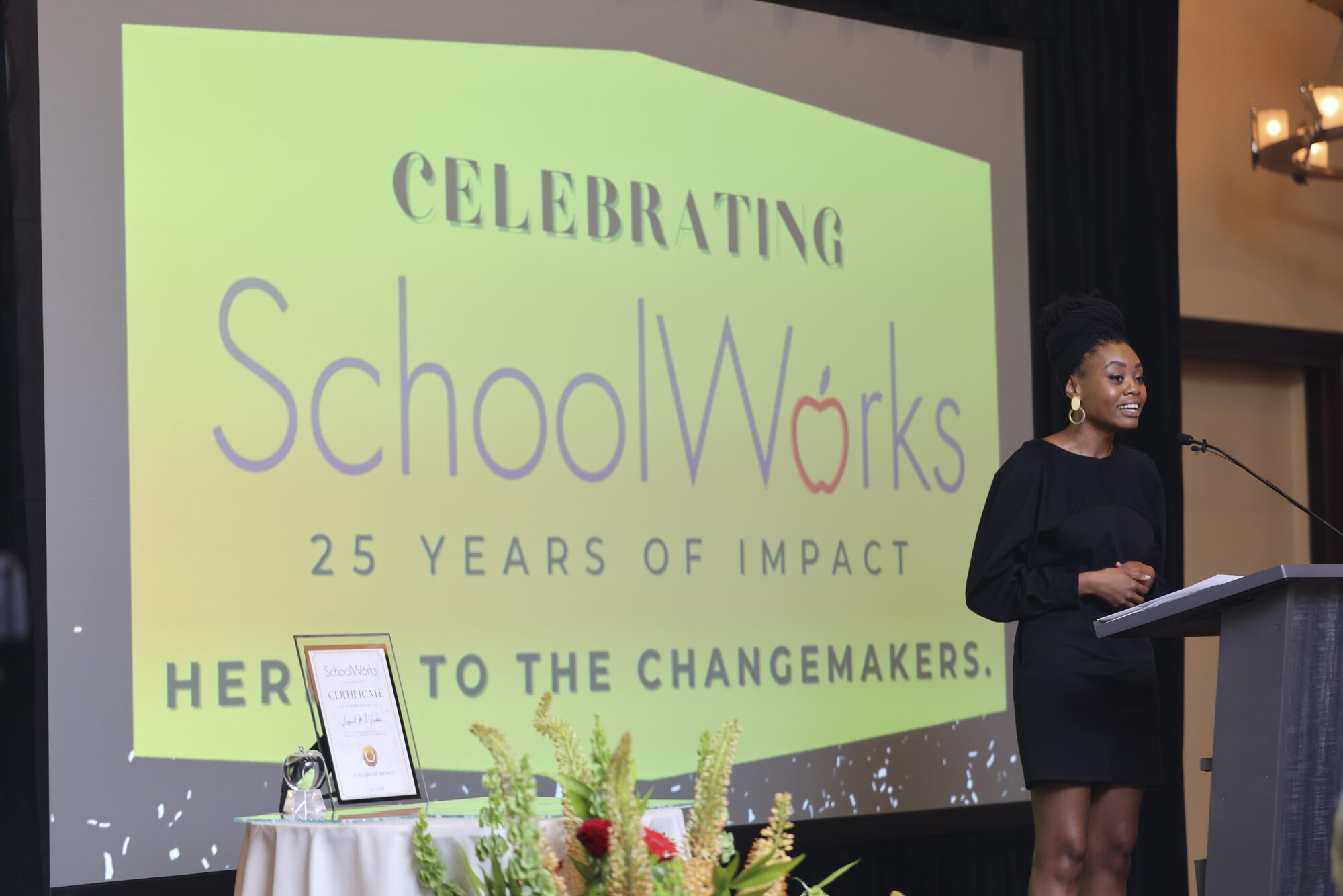 Mariah Scott speaking at a podium, celebrating SchoolWorks' years of impact